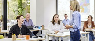 Deutschlernende sitzen in einem Klassenzimmer und h�ren ihrer Deutschlehrerin zu.