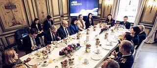 A group of people sit around a laid table at the Munich Security Conference 2024.